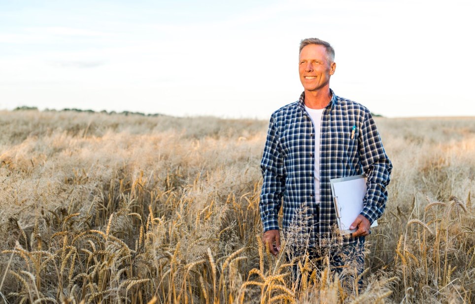 a man standing and smiling in a wheat field