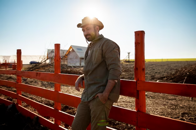 Male farmer posing next to fence on farm